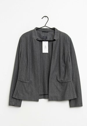 Grå pindstribet blazer med åben front og lange ærmer, hængende på en sort bøjle mod hvid baggrund.