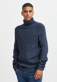 Temno mornarsko modra turtleneck pulover iz rebraste pletenine; dolgi rokavi; oprijet kroj z debelim, strukturiranim ovratnikom.