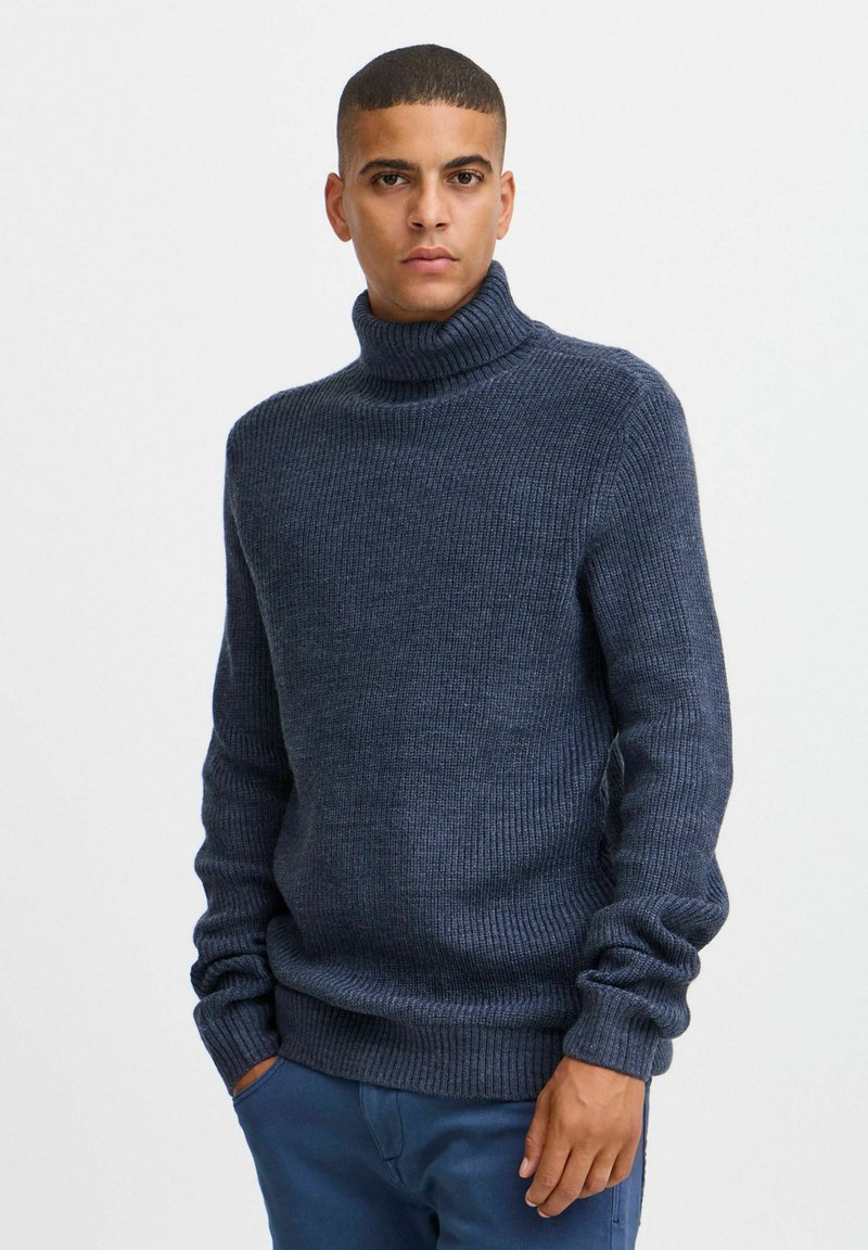 Temno mornarsko modra turtleneck pulover iz rebraste pletenine; dolgi rokavi; oprijet kroj z debelim, strukturiranim ovratnikom.