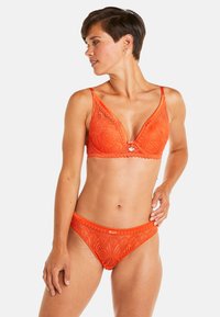 Un soutien-gorge en dentelle orange et un bas de bikini assorti présentent un motif floral, des bords festonnés et un petit accent en forme de cœur à l'avant.