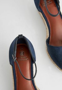 Espadrillas in camoscio blu navy con punta rotonda, cinturino alla caviglia e soletta in cuoio marrone con il marchio "Forever Comfort" e suola in juta intrecciata.