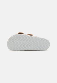Sneakersula med en strukturerad vit gummikant, med ett vågmönster. Bruna accenter och en rundad tådesign.