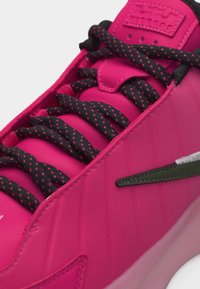Φωτεινό ροζ αθλητικό παπούτσι με κορδόνια μαύρου και ροζ χρώματος με στίγματα, επενδυμένη γλώσσα και μικρό σκοτεινό πράσινο λογότυπο Nike στο πλάι.