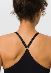 Schwarzes Tanktop mit verstellbaren Trägern, das ein Ringdetail auf der Rückseite und eine glatte, dehnbare Stoffstruktur aufweist.