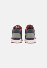 Sneakers Timberland z granatową cholewką, szarym panelem na pięcie, czerwonym wykończeniem i nakrapianą białą podeszwą. Posiadają wyściełany kołnierz i logo z tyłu.