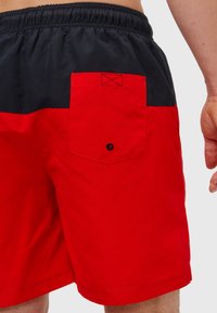 Røde og marineblå badshorts med elastisk livlinje, sidelommer og en baklomme med klaff som har knappdetalj og kontraststing.