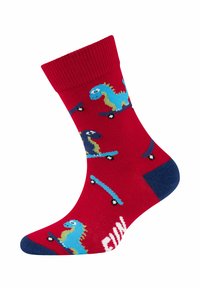 Calze rosse con dinosauri dei cartoni animati su skateboard, con accenti blu e una texture tipica dei materiali in misto cotone. La scritta recita "DIVERTENTE."