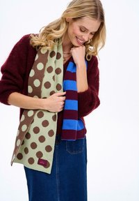 Dva šály: jeden zelený s hnedými bodkami a jeden pruhovaný modro-vínový. Oba sú pletené z jemného, mäkkého materiálu.