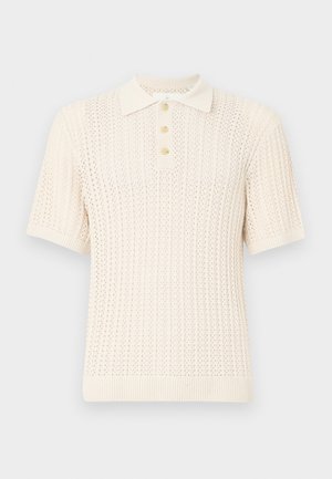 Short-sleeve polo shirt in light cream, featuring a textured knit pattern, ribbed collar, and button placket with four buttons.