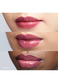Lipproducten in verschillende tinten mauve en roos. Glanzende afwerking, volle lippen, drie monsters verticaal weergegeven met het label "SLOW JAM."