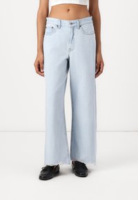 Ljusblå vida denimjeans med råkant, fem fickor och subtila sömdetaljer. Matchas med svarta skor.