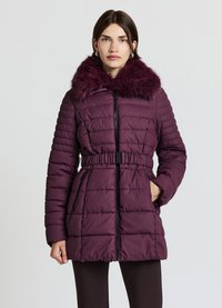 Veste matelassée bordeaux avec col en fausse fourrure, texture matelassée, taille ceinturée et fermeture éclair frontale. Idéale pour le port par temps froid.