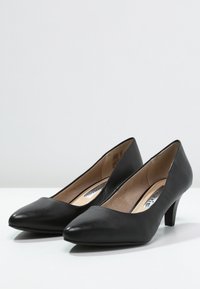 Svarta läder högklackade skor med en spetsig tådesign och en 5 cm klack. Har en slät textur och en subtil detaljerad innerventil.