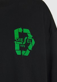 Schwarzes T-Shirt mit einem grünen Recycling-Logo, in das der Text "DIESEL 1978" integriert ist. Der Stoff wirkt weich und hat eine entspannte Passform.