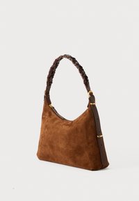Sac à épaule en daim marron avec une anse tressée marron foncé. Équipé de quincaillerie dorée et d'une sangle en cuir lisse pour une longueur ajustable.