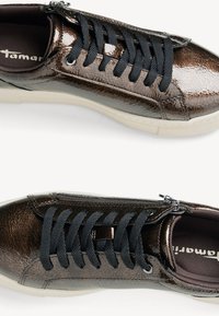 Bruna patentlädersneakers med svarta snören, rundad form, texturerad yta och off-white gummisula. Sidoblixtlåsdetaill.