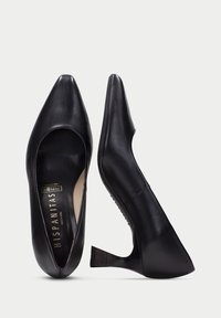 Zapatos de tacón alto de cuero negro con punta afilada, diseño de corte curvado y acento texturizado en el tacón. Acabado suave.