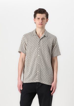 Camisa de manga corta con botones en un patrón a cuadros, que presenta colores beige y negro, con un ajuste relajado y una textura de tela suave.