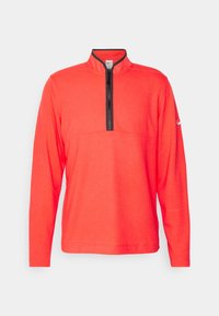 Pull-over rouge vif à manches longues avec col à demi-zip noir et petit logo sur la manche gauche, présenté sur fond blanc.