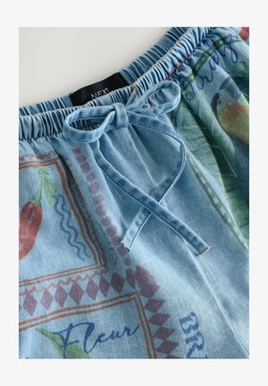 Shorts in denim azzurro chiaro con vita elasticizzata, dotati di un cordino e stampe floreali e geometriche vibranti in rosa e verde.