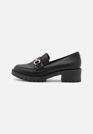 Mocassin en cuir noir avec talon épais, détail en métal doré sur le dessus, semelle texturée, et "BIANCO" embossé près du talon.