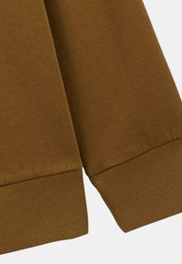 Tissu de sweat-shirt marron avec des poignets côtelés. Texture lisse avec une couleur uniforme et des détails de couture soignés le long des bords.