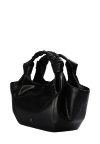 Zwarte leren tote bag met gevlochten handvatten, gestructureerde vorm, zachte textuur en een klein schedelembleem aan de zijkant.