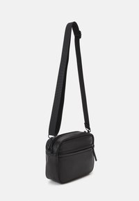 Černá crossbody taška z hladké kůže s obdélníkovým tvarem, zipovým uzávěrem a nastavitelným popruhem. Má přední kapsu.