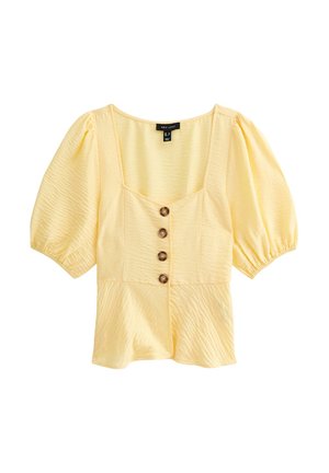 Blouse jaune texturée avec des manches bouffantes, décolleté carré et trois boutons marron sur le devant. Confectionnée en tissu léger.