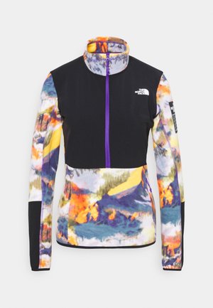 Veste polaire à manches longues avec col montant, panneau poitrine noir, fermeture éclair violette et motif abstrait multicolore sur les manches et le bas.