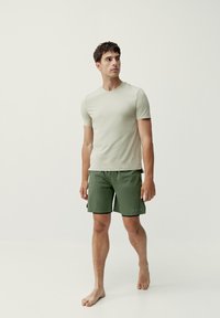 Gaiši zaļa īsām piedurknēm krekliņa kombinācija ar tumši zaļiem šortiem. Krekliņam ir apaļa kakla izgriezums; šortiem ir elastīga jostasvieta un redzama šuvuma detaļa.