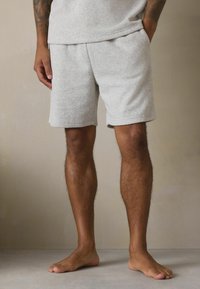 Hellgraue, weiche Stoffshorts mit elastischem Bund. Mit Seitentaschen und einem lässigen Schnitt, der über dem Knie endet.