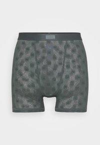 Boxer shorts vert foncé avec un design en mesh, arborant un motif de formes épineuses. Ceinture douce avec une petite étiquette logo à l'avant.