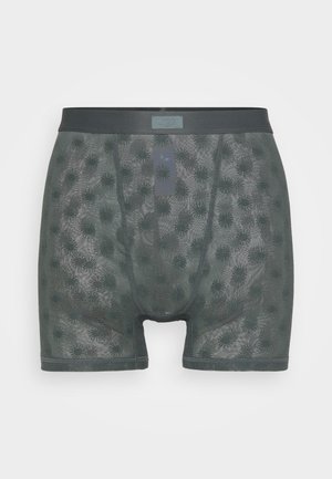 Dunkelgrüne Boxer-Shorts mit einem Mesh-Design, das ein Muster aus stacheligen Formen zeigt. Weicher Bund mit einem kleinen Logotag auf der Vorderseite.