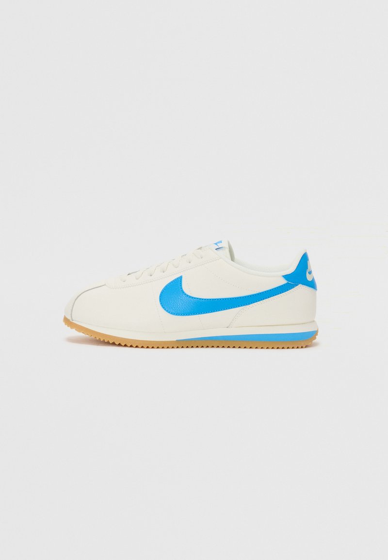Vīriešu sporta apavi ar krēmbaltu ādas augšdaļu, zilu Nike zīmi un ziliem akcentiem; aprīkoti ar gumijas zoli ar strukturētu rakstu, kas nodrošina saķeri.