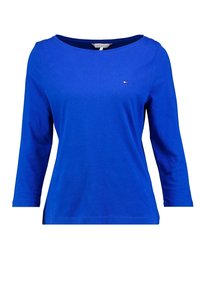 Blå långärmad topp i bomull, med rund halsringning och en liten logodetalj på bröstet. Slät textur med en figursydd design.