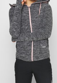Gray knit zip-up hoodie with pink zipper and drawstrings, long sleeves, and fitted design. Logo displayed on the lower front.