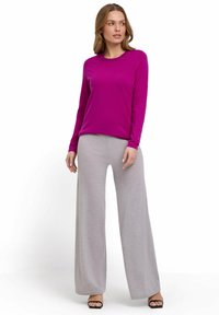 Fuchsia top met lange mouwen in combinatie met lichtgrijze brede broek. Gekenmerkt door zachte stof met een ontspannen pasvorm en een ronde halslijn.