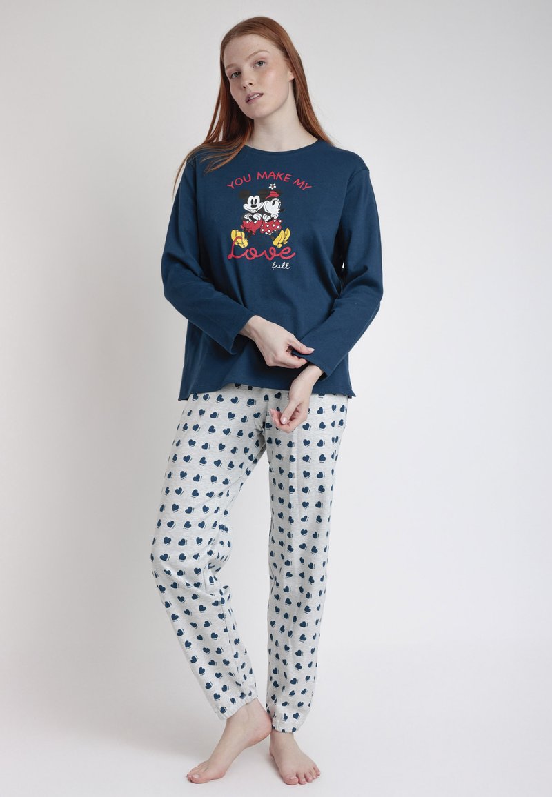 Camisa de pijama de manga larga en color navy con un gráfico blanco y rojo que presenta personajes, combinada con pantalones gris claro decorados con patrones de corazones azul oscuro.