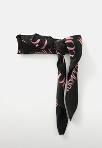 Fekete selyemkendő, amelyen nagy rózsaszín betűk láthatók; masni formában csavart, hosszú, hegyes végekkel. Simaság jellemzi és fényes a felülete.