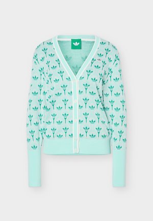 Ανοιχτό τιρκουάζ καζάκα με κουμπιά, μακριά μανίκια και ολόκληρο μοτίβο με σκούρο πράσινο λογότυπο τριφύλλι, άσπρη επένδυση κατά μήκος της λαιμόκοψης και των κουμπιών.