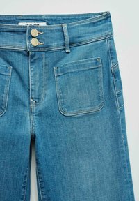 Blue denim jeans with front patch pockets, double button closure, and belt loops, laid flat on a light background.