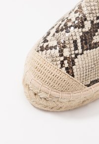 Woven espadrille with a beige jute sole and a textured snakeskin pattern in black and cream on the upper. Rounded toe design.