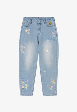 Hele sinised teksapüksid, millel on tikitud mitmevärvilised lilled ja väike mesilase plaastrie esitasku lähedal.