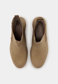 Bottines en cuir tan avec des panneaux latéraux élastiques, bout rond et intérieur texturé et rembourré. Semelles en caoutchouc plates avec un léger profil.