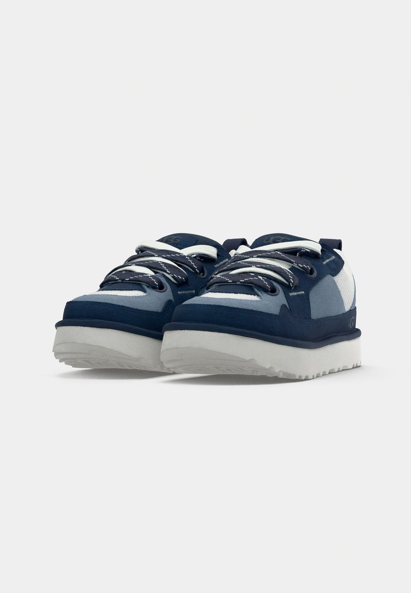 Zapatillas navy y azul claro con un upper texturizado, cordones blancos y una suela de goma blanca gruesa; presentan un diseño deportivo y punta reforzada.