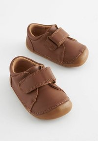 Chaussures en cuir marron pour tout-petits avec une bande velcro, bout arrondi et détails de couture contrastants. Intérieur doux et semelle en caoutchouc flexible.