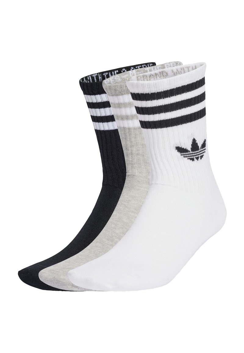 Trzy pary skarpetek załogowych w kolorze czarnym, szarym i białym, z prążkowaną teksturą, trzema poziomymi paskami oraz logo Adidas po boku.
