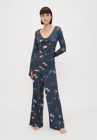 Σετ πιτζάμας ναυτικού χρώματος με λουλούδια, με μακριά μανίκια και παντελόνι καμπάνα, που διαθέτει κάθετες ρίγες και ζωντανές κεντητές λεπτομέρειες.