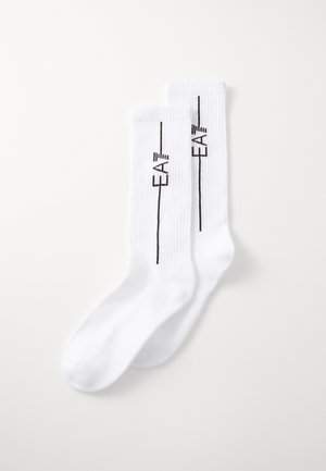 Socks de algodão brancos com textura canelada. Apresenta um logotipo impresso preto "EA7" ao lado de uma linha vertical preta.